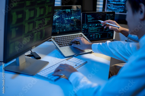 It professional analyzing code and data on multiple screens in a modern office.