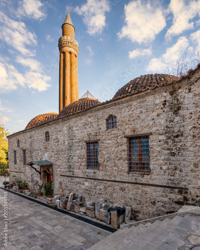 Historic Yivli Minare Mosque featuring its iconic fluted minaret and ancient stone architecture in the old town of Antalya, Turkey, set against a beautiful blue sky during the late afternoon