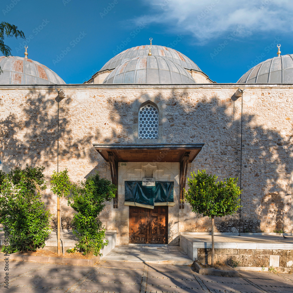 Fototapeta premium Exterior view of the historic Tekeli Mehmet Pasa Mosque featuring stone masonry and lead-covered domes in the old town district of Antalya, Turkey