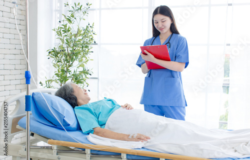Foto Asian woman nurse visit inquire condition senior female patient resting in hospital bed compassion healthcare support quality elderly  recovery nursing assistance medical treatment wellness services