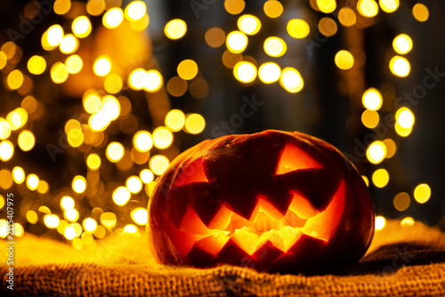Spooky Halloween pumpkin lantern sitting on a table with warm bokeh background