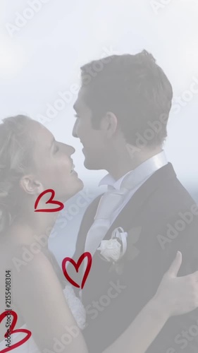 Animation of red hearts over caucasian couple wearing wedding clothes and talking