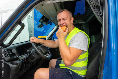 Truck driver eating a fresh apple while driving a commercial vehicle
