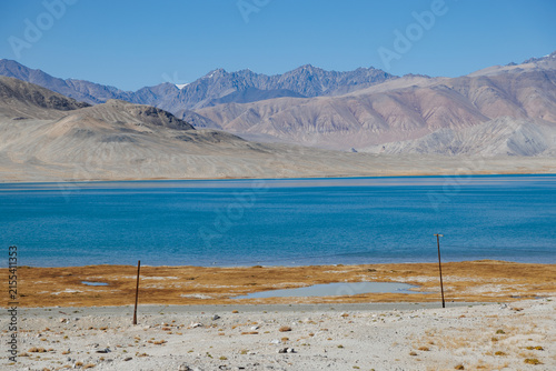Fotografie Deep blue Karakul Lake with border fence poles in Eastern Pamir near Chinese bor