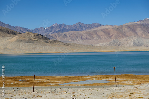 Bild auf Leinwand Scenic view of turquoise alpine lake Karakul surrounded by arid mountains along