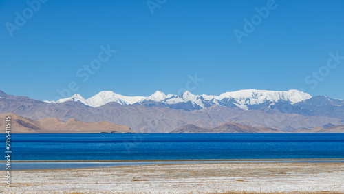 Obraz na płótnie Scenic high-altitude salt lake Karakul with snowy peaks backdrop along Pamir Hig