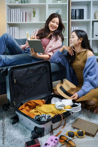 Two asian friends woman packing suitcase and choosing item together, planning a trip, checking in note or packing lists, travel preparation, Planning Vacation Trip with Excitement