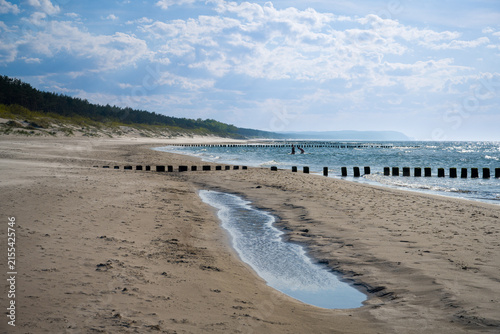 Fotografie Sandy beach with wooden breakwater groynes in Dziwnow Poland
