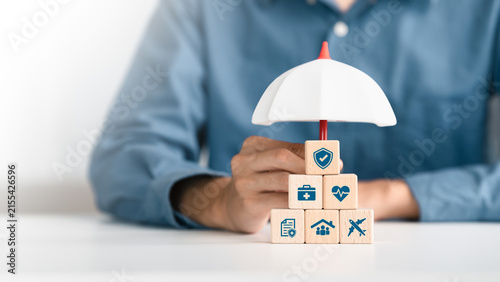 Healthcare, life and travel insurance concept on wooden cube under an umbrella for safety, medical and planning in Future. investment and retirement.