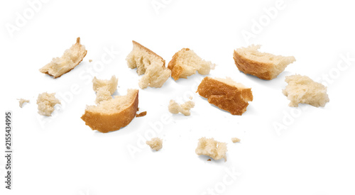 Fotografía Several pieces of broken bread crusts and crumbs are scattered across a plain white background