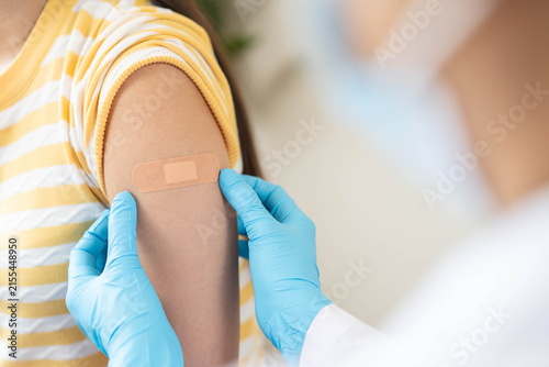 Foto Close up of doctor applying adhesive bandage on girl arm after vaccination