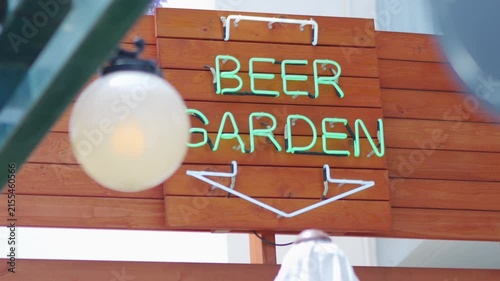A beer garden sign with green text on a wooden background in an outdoor social setting in 4K slow motion 120fps