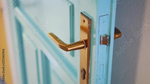 A close-up of a golden door handle on a pastel-colored door in 4K slow motion 120fps