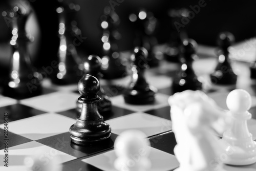 Foto Black chess pawn on board with blurred pieces and dramatic lighting conveying st