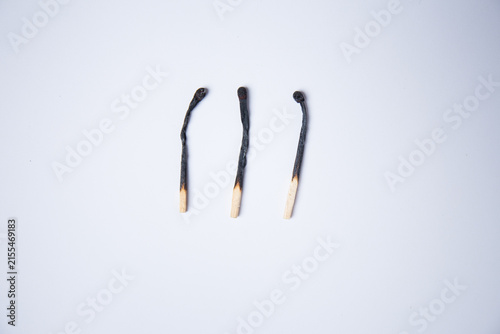 Three used, burnt matchsticks against a white background