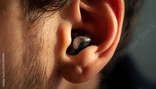 Close-up of a person's ear with a small, discreet earbud inserted into the canal