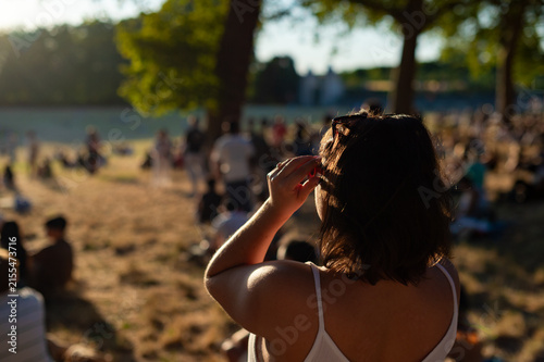 Fotografía A woman uses solar eclipse glasses to look at the sky in a park crowd during a public astronomical event