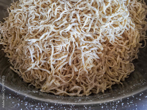 Fresh hand shredded dried tofu strips piled in metal bowl, textured vegetarian protein ready for cooking and savory meals