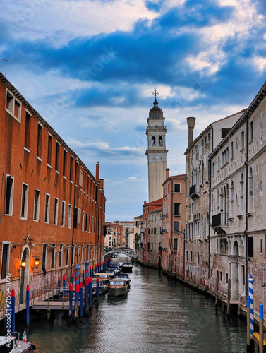 Cuadro en lienzo Narrow canal with moored motorboats and the leaning bell tower of San Giorgio de