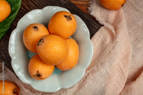 Quadro su tela Fresh Loquats in a Ceramic Bowl on Rustic Table