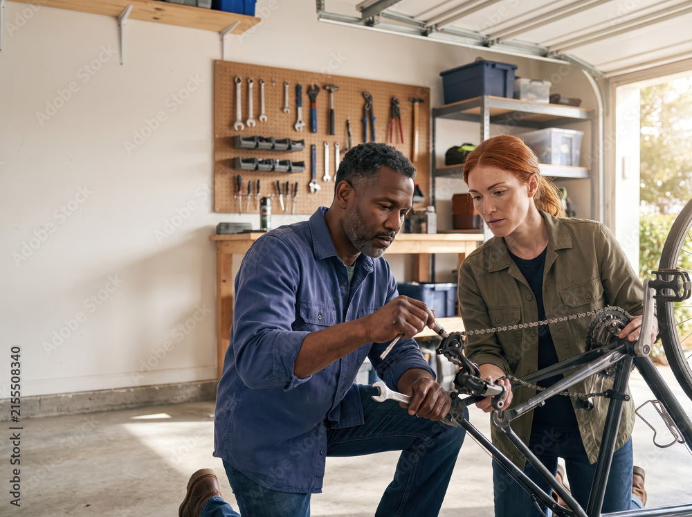 Fototapeta premium Two people repairing a bicycle in a garage during a sunny day
