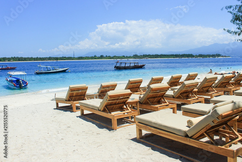 Gili Trawangan beach with wooden sunbeds, white sand, and boats on turquoise water in Lombok