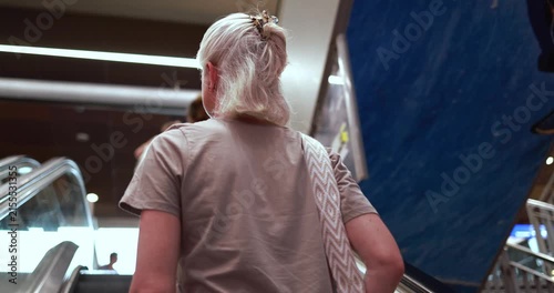 Caucasian 50's woman on escalator wearing casual clothes - City lifestyle, travel and elderly person concept - UGC content