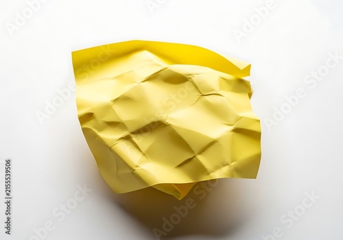 A crumpled yellow piece of paper on a white surface