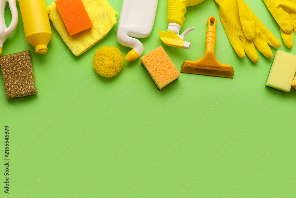 Fototapeta premium Assortment of yellow and orange Cleaning supplies and products arranged on a bright green background with copy space