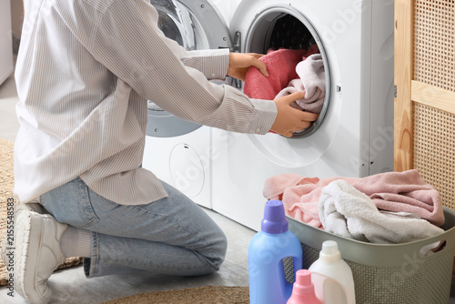Fotografía Woman taking colorful towels from washing machine in room