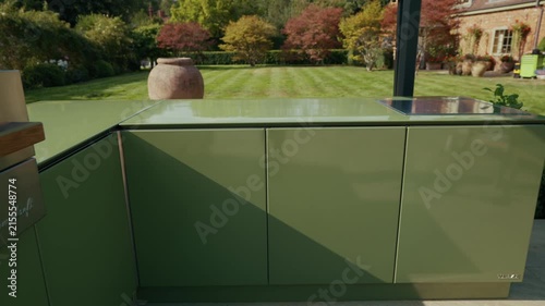 Green outdoor kitchen counter reflects a lush London garden scene
