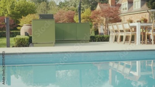 Modern green outdoor kitchen setup beside a luxurious swimming pool