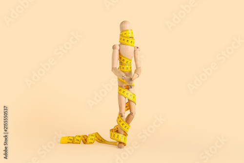 Fotografie Wooden mannequin doll with measuring tape on beige background
