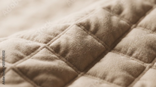 Quilted fabric texture displays a square stitched pattern on beige padded material.