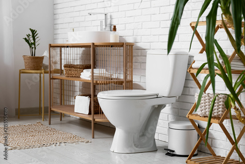 Interior of restroom with toilet bowl  sink and shelf units