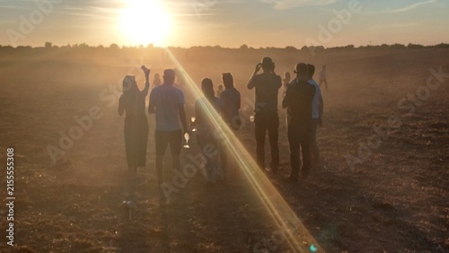 Gruppe von Menschen schaut auf einem Stoppelacker in die Abendsonne der partiellen Sonnenfinsternis