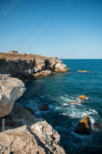 Scenic rocky coastline with turquoise sea water, cliff and rocks on a sunny day