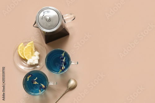 Foto Teapot and cups with butterfly pea flower tea on beige background