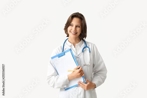 Beautiful female doctor with clipboard on white background