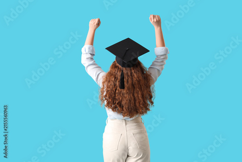 Female student in graduation hat on blue background, back view
