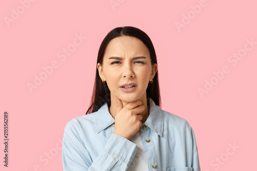 Bild auf Leinwand Beautiful young woman suffering from sore throat on pink background