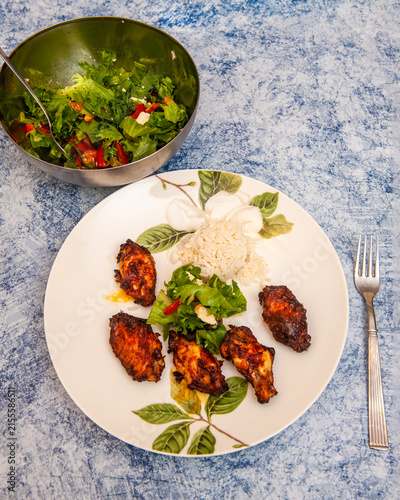 Homemade Chicken Wings Baked in an Air Fryer with Rice on a Plate and Salad in a Bowl.