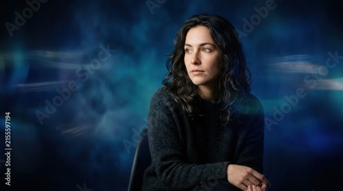 Thoughtful Woman Gazing Sideways Against Moody Blue Background.