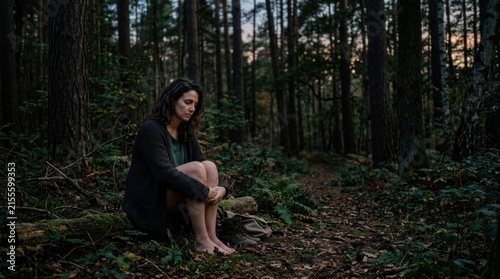 Young Woman Sitting Alone in Dark Forest at Dusk.