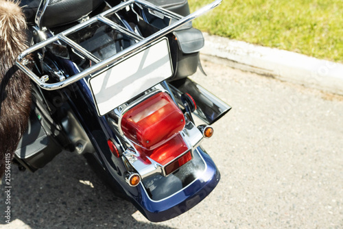Foto Rear view of dark blue motorcycle parked on asphalt road during sunny day, showc