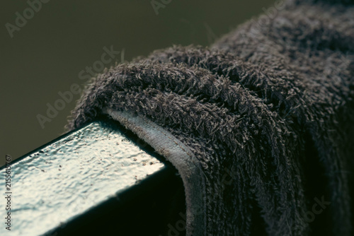 Extreme macro close-up of a soft, gray terry cloth towel draped over a wet, glossy railing with a muted background