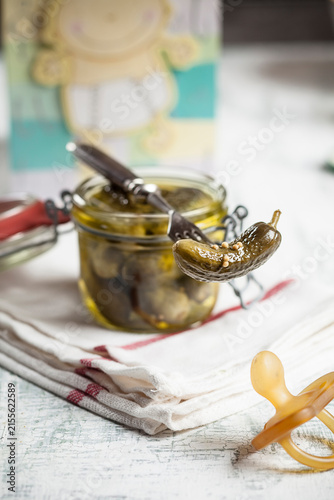 Pickled cornichons in preserving jar, fork and dummy