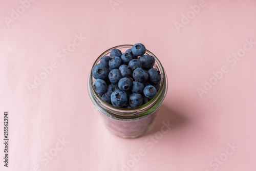 Принти на полотні Glass jar filled with blueberries on pastel pink background