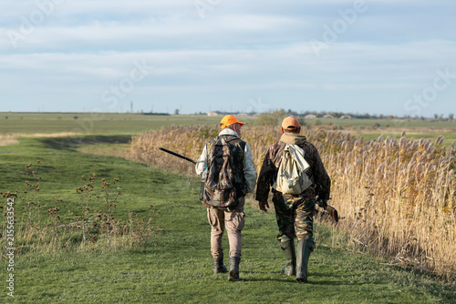 Foto A hunters in camouflage clothing with a gun in his hands walks along the reeds