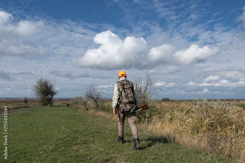 A hunter with a gun in camouflage clothing. A gentleman with a gun, medium shot, unrecognizable.